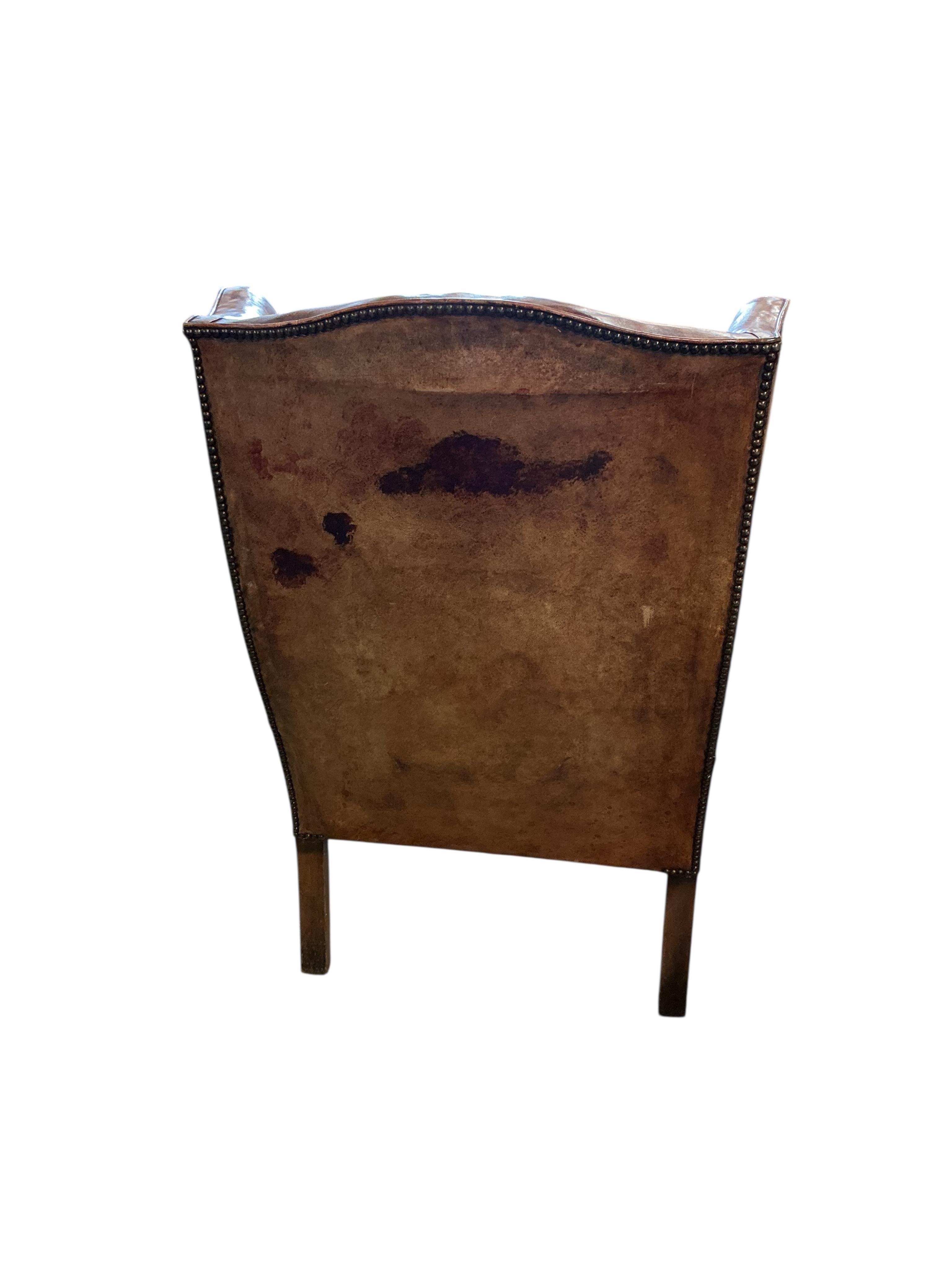 A George III style studded pale red leather wing armchair on carved oak cabriole legs, width 74cm, depth 78cm, height 110cm